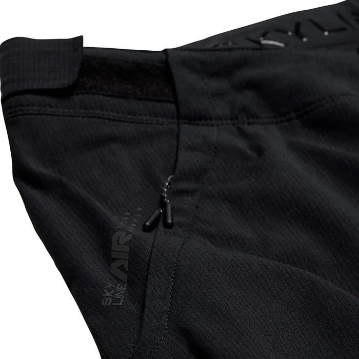 Close-up of black pants with a brand logo on a white background