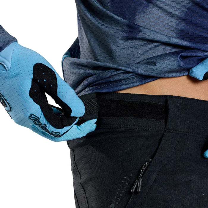 Person wearing blue gloves and black pants with a white background