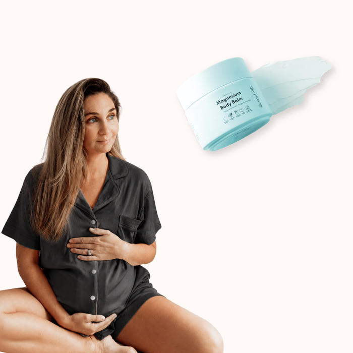 Sleepybelly Comfort Bundle: pregnant woman in charcoal maternity pyjamas with Magnesium Body Balm