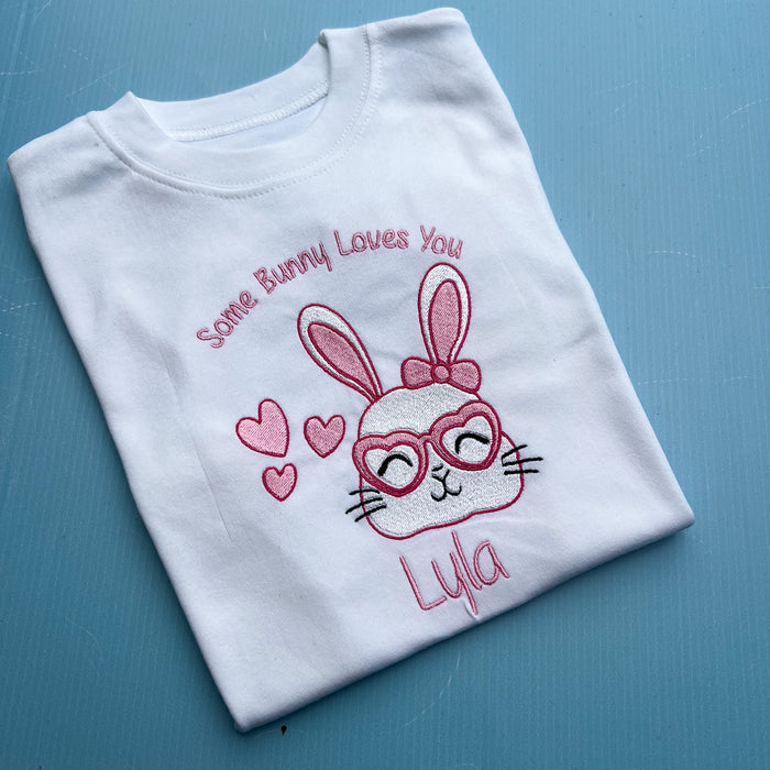 Folded white t-shirt with a bunny design and text on a blue surface