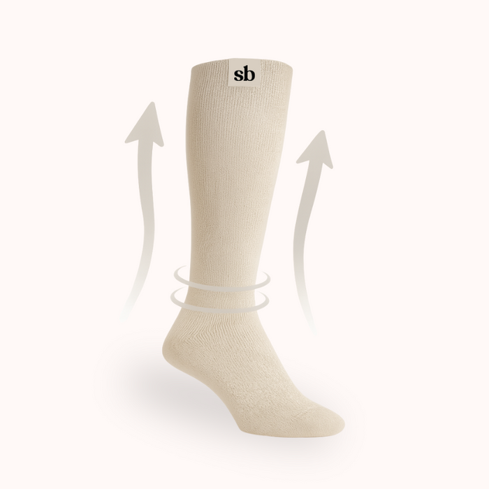 Pink Sleepybelly maternity compression sock with arrows showing graduated compression moving blood flow upward