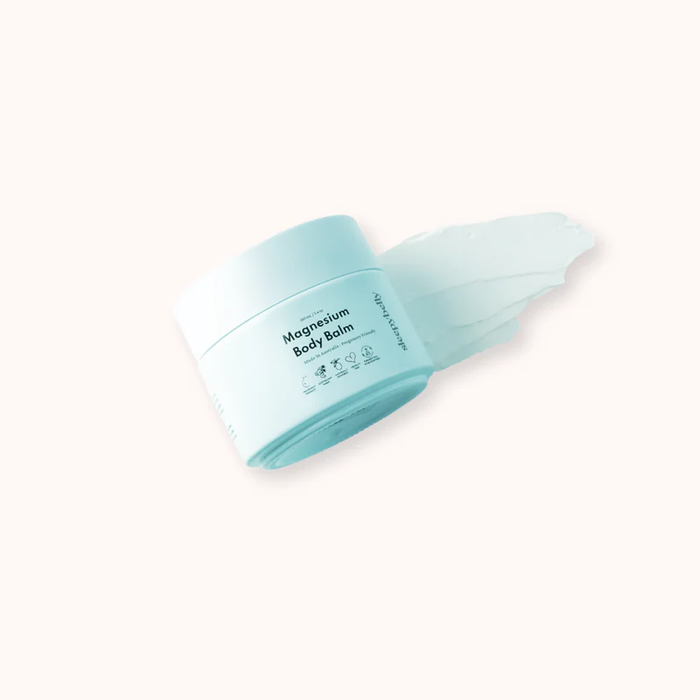 Sleepybelly Magnesium Body Balm tub tilted over a smear of cream on a soft cream background