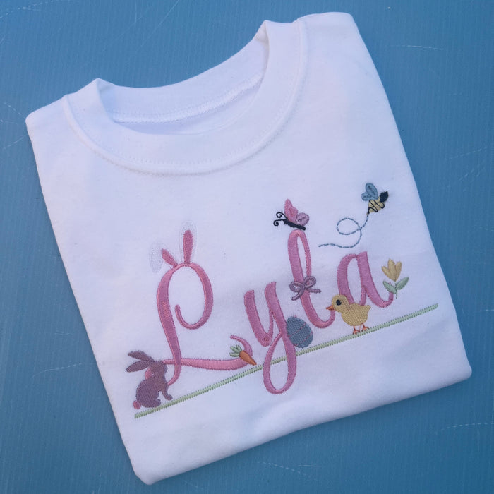 Name Lyla with lots of little Easter icons attached to it, Easter ears, bunny, carrot, bumble bee, flowers and chicks