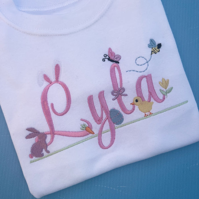Name Lyla with lots of little Easter icons attached to it, Easter ears, bunny, carrot, bumble bee, flowers and chicks