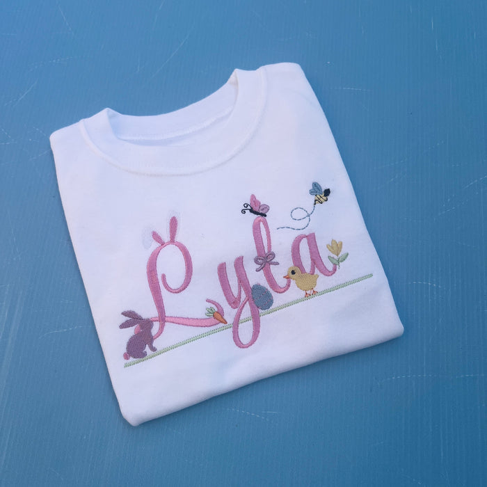 Name Lyla with lots of little Easter icons attached to it, Easter ears, bunny, carrot, bumble bee, flowers and chicks