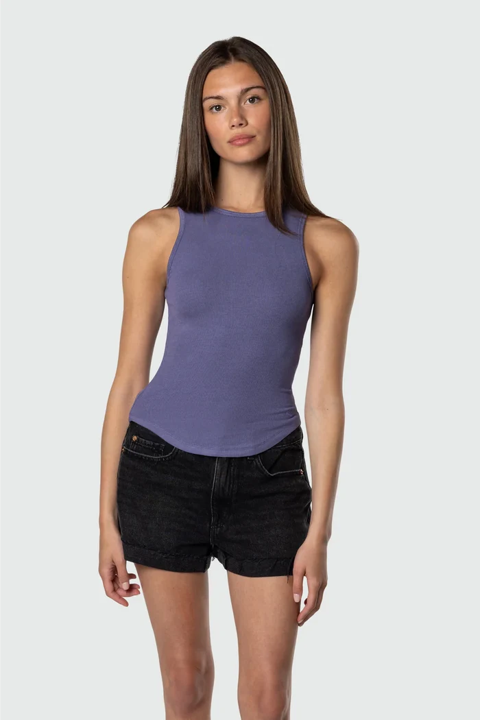 Woman wearing a purple tank top and black shorts on a white background