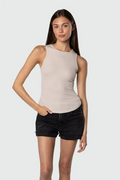 Woman wearing a beige tank top and black shorts on a white background