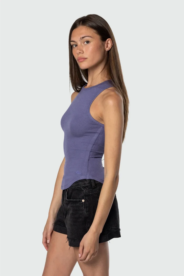 Woman wearing a purple sleeveless top and black shorts on a white background