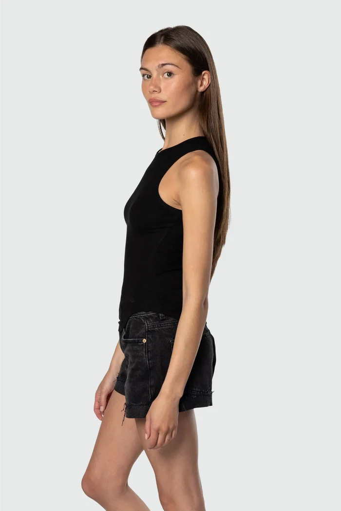 Woman wearing a black sleeveless top and black shorts on a white background
