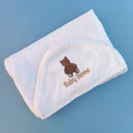 White baby towel with brown teddy bear design and 'Baby Denne' text on a blue background