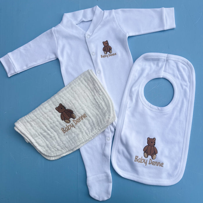 Baby clothing set with white shirt, bib, and diaper on a blue background