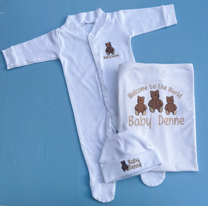 Baby clothing set with white onesie, hat, and blanket on a blue background