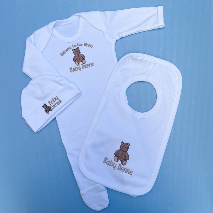 Baby clothing set with bib, hat, and blanket on a blue background