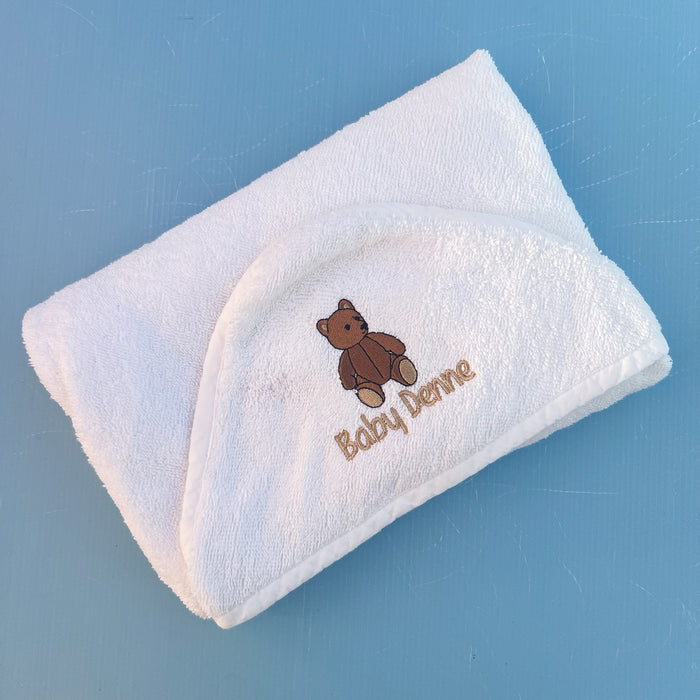 White baby towel with brown teddy bear design and 'Baby Dove' text on a blue background