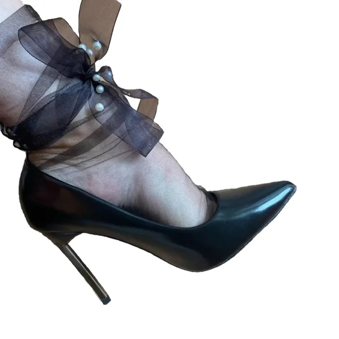 Model wearing sheer ankle socks with long pearl-accented ribbon ties in black styled with heels for coquette or punk fashion