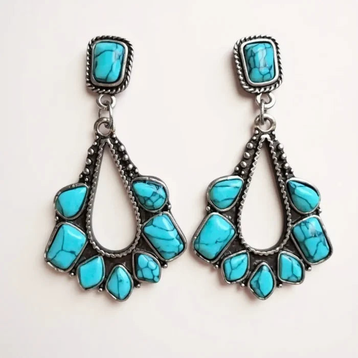 silver-plated turquoise teardrop western earrings on off white background