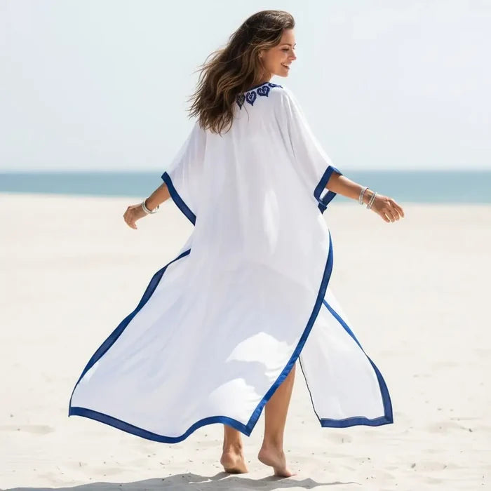 White Blue Embroidered Resort Kaftan flowing on the beach with blue embroidery accent.
