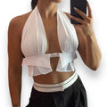 White sleeveless wrap around halter crop top with backless design, tie-back neckline, and cut-out front, styled for Y2K summer festival and beach fashion.