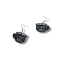 Witches Brew Acrylic Tea Cup Earrings in black with double-sided pink and white lettering and fish hook dangles flat lay