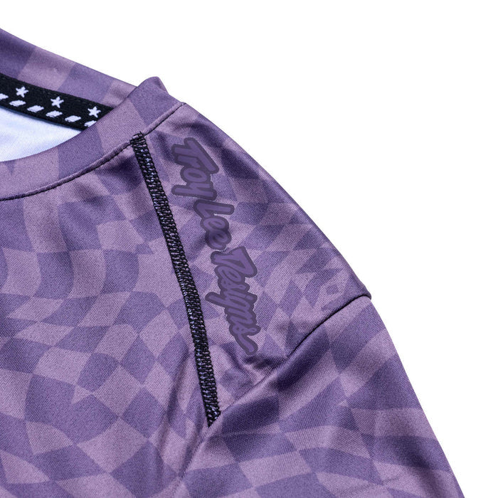 Close-up of a purple checkered shirt with a brand logo on a white background