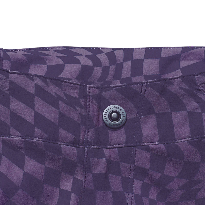 Close-up of a purple checkered fabric with a button, featuring a brand logo.