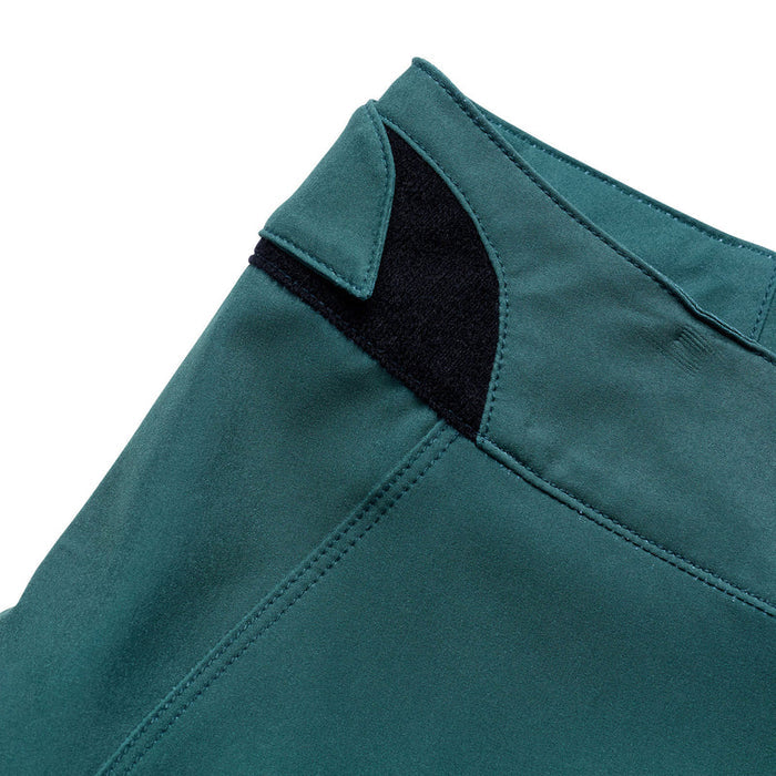 Close-up of teal pants with a black lining on a white background