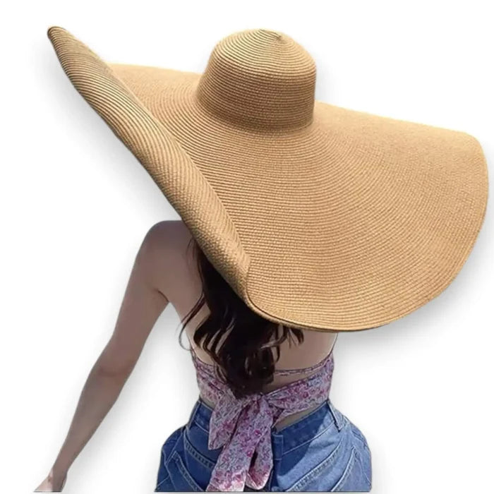 woman wearing brown Women’s Oversized Brim Straw Sun Hat with dramatic 10-inch asymmetrical brim and woven straw beach style