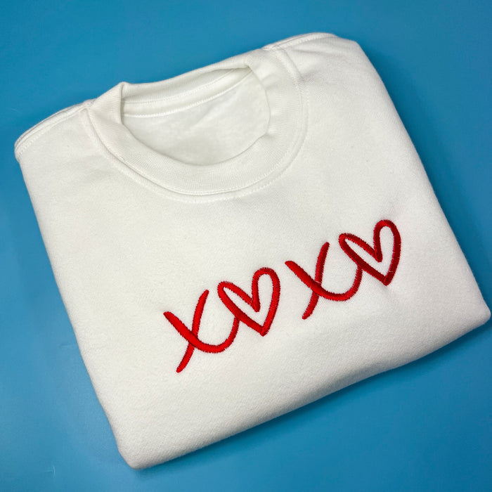 White crew neck sweatshirt with red heart text design on the front.