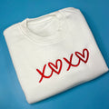 White crew neck sweatshirt with red heart text design on the front.